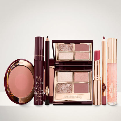 An open two-tone blush in cool-toned brown and warm pink with a mascara, eyeliner pencil, quad eyeshadow palette with shimmery and matte brown and golden shades, an open lipstick in nude red, lip liner pencil in maroon and a lip gloss in nude pink.