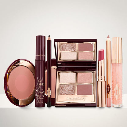 An open two-tone blush in cool-toned brown and warm pink with a mascara, eyeliner pencil, quad eyeshadow palette with shimmery and matte brown and golden shades, an open lipstick in nude red, lip liner pencil in nude pink, and a lip gloss in nude pink.