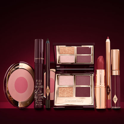 An open, mirrored-lid eyeshadow palette in matte and shimmery gold and red shades, an open black eyeliner pencil, a mascara in a dark-crimson colour scheme, a red lipstick with a matching lip liner pencil, vampy-red lip gloss, and an open two-tone blush in cool pink.