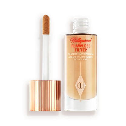An open glow-boosting primer in a glass bottle with a rose gold-coloured lid with a doe-foot applicator.